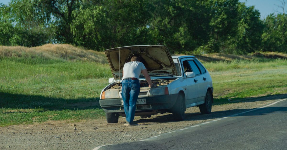 conductor de pie junto a su auto detenido en la carretera